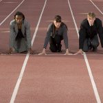 Five adults in business attire ready to run a race on a track