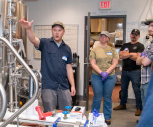 Brewing course instructor shows students professional brewing equipment.