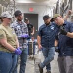 Surrounded by big silver vats, the teacher at Brewing Science course explains the workings of a brewery to his students.