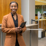 Joy Dufitumukiza standing in front of Morris Library turnstiles.