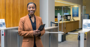 Joy Dufitumukiza standing in front of the turnstiles at the entrance to the Morris Library.